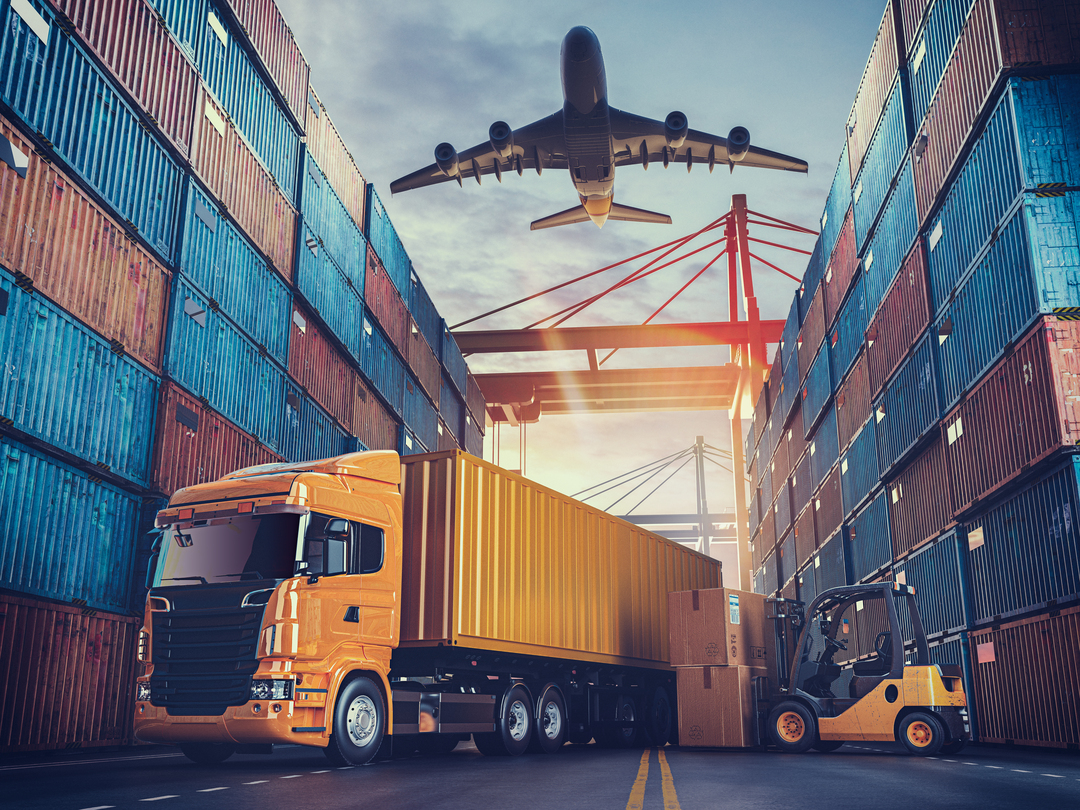 sazonalidade-na-logistica Sazonalidade na logística: caminhão amarelo manobra em pátio com avião passando no céu acima.